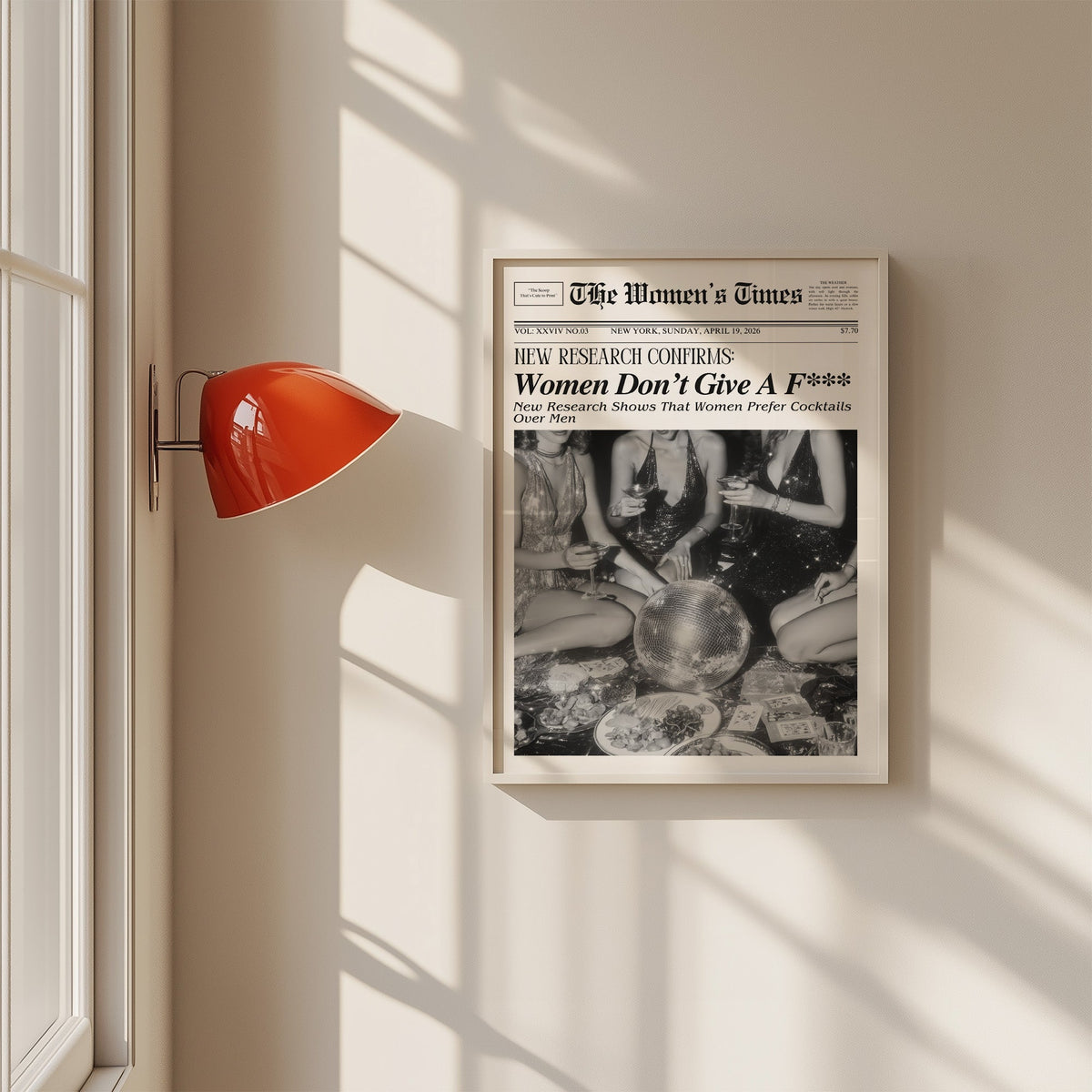Mock front page with women around a disco ball print in a white frame on a sunlit wall beside a red sconce