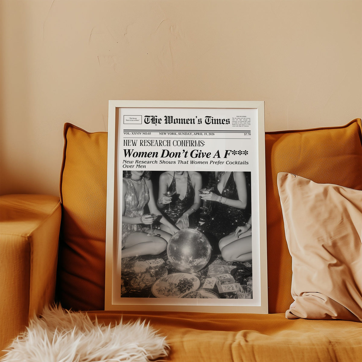 Mock front page with women around a disco ball print in a white frame leaning on a mustard velvet sofa