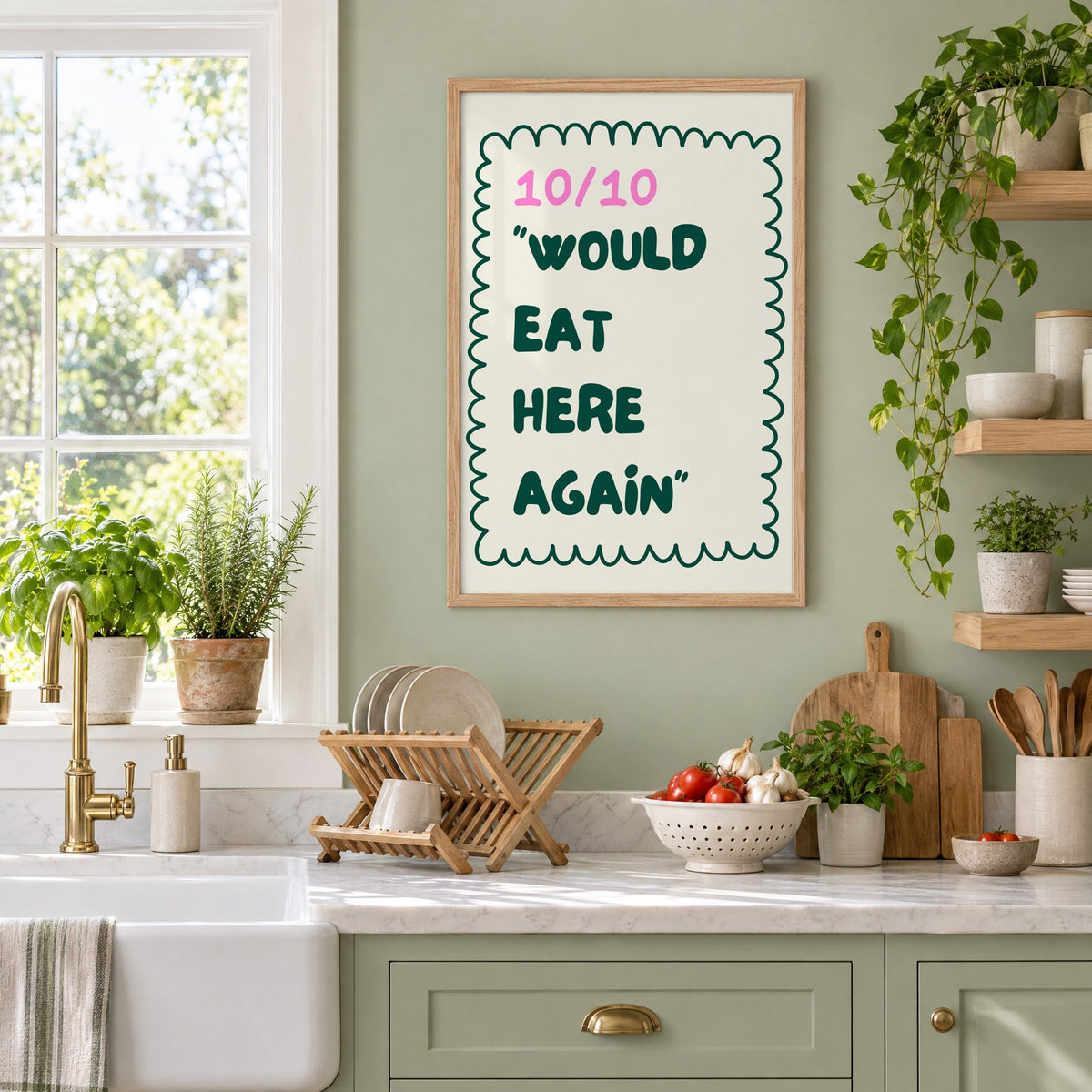 Would Eat Here Again 10/10 print in an oak frame on a sage green kitchen wall beside a farmhouse sink and herbs