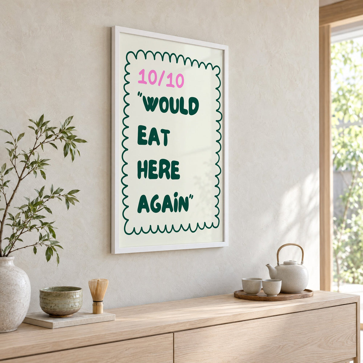 Would Eat Here Again 10/10 print in a white frame above a pale wood console with a matcha tea set