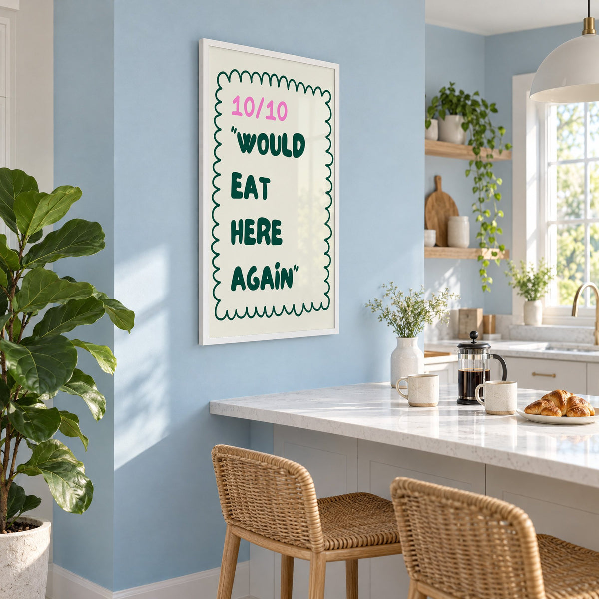 Would Eat Here Again 10/10 print in a white frame on a pale blue wall above a breakfast bar with rattan stools