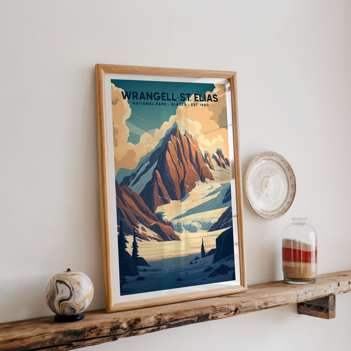 Wrangell–St. Elias National Park print in an oak frame on a wood shelf with ceramics and a sand jar