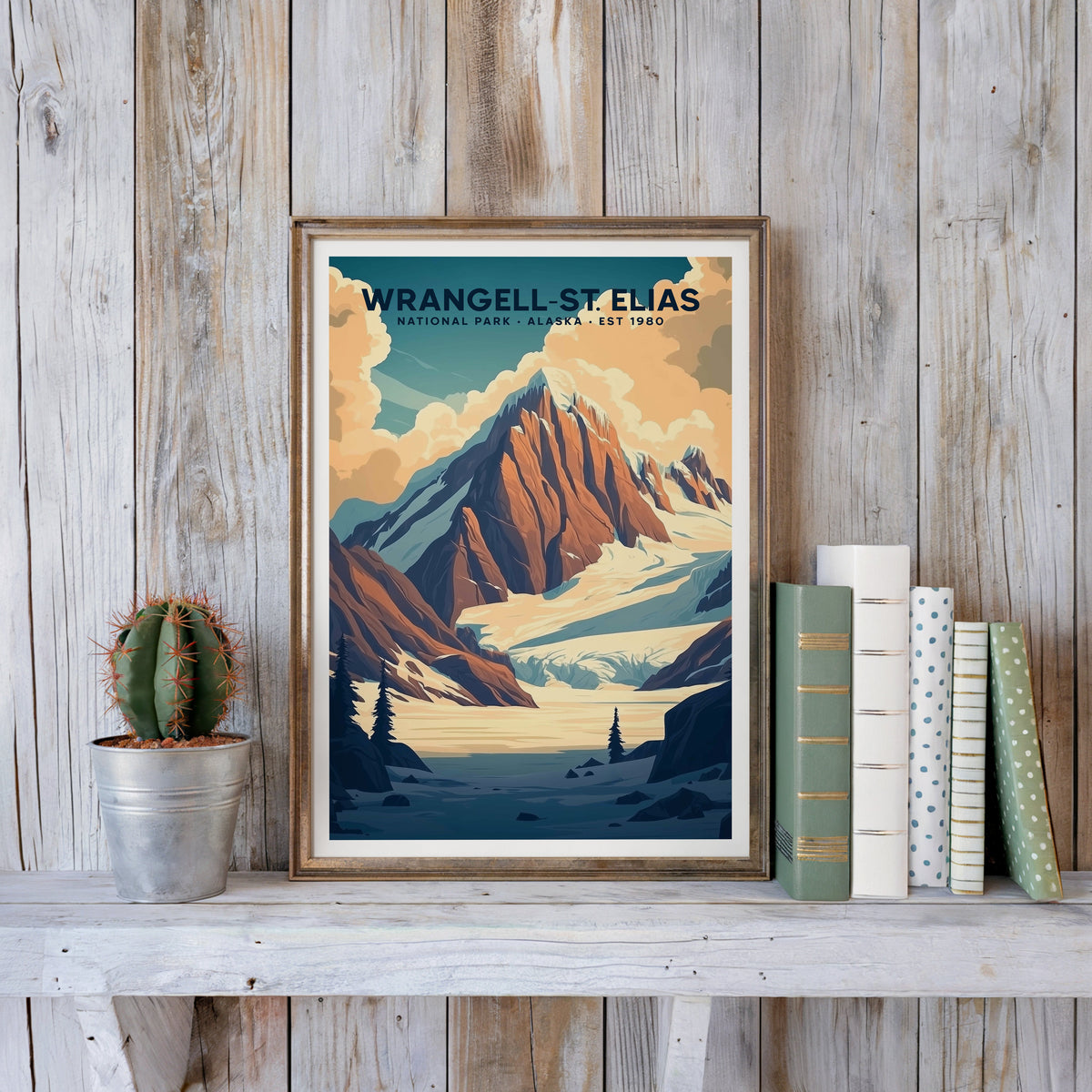 Wrangell–St. Elias poster in an antique gold frame against whitewashed planks beside books and a cactus