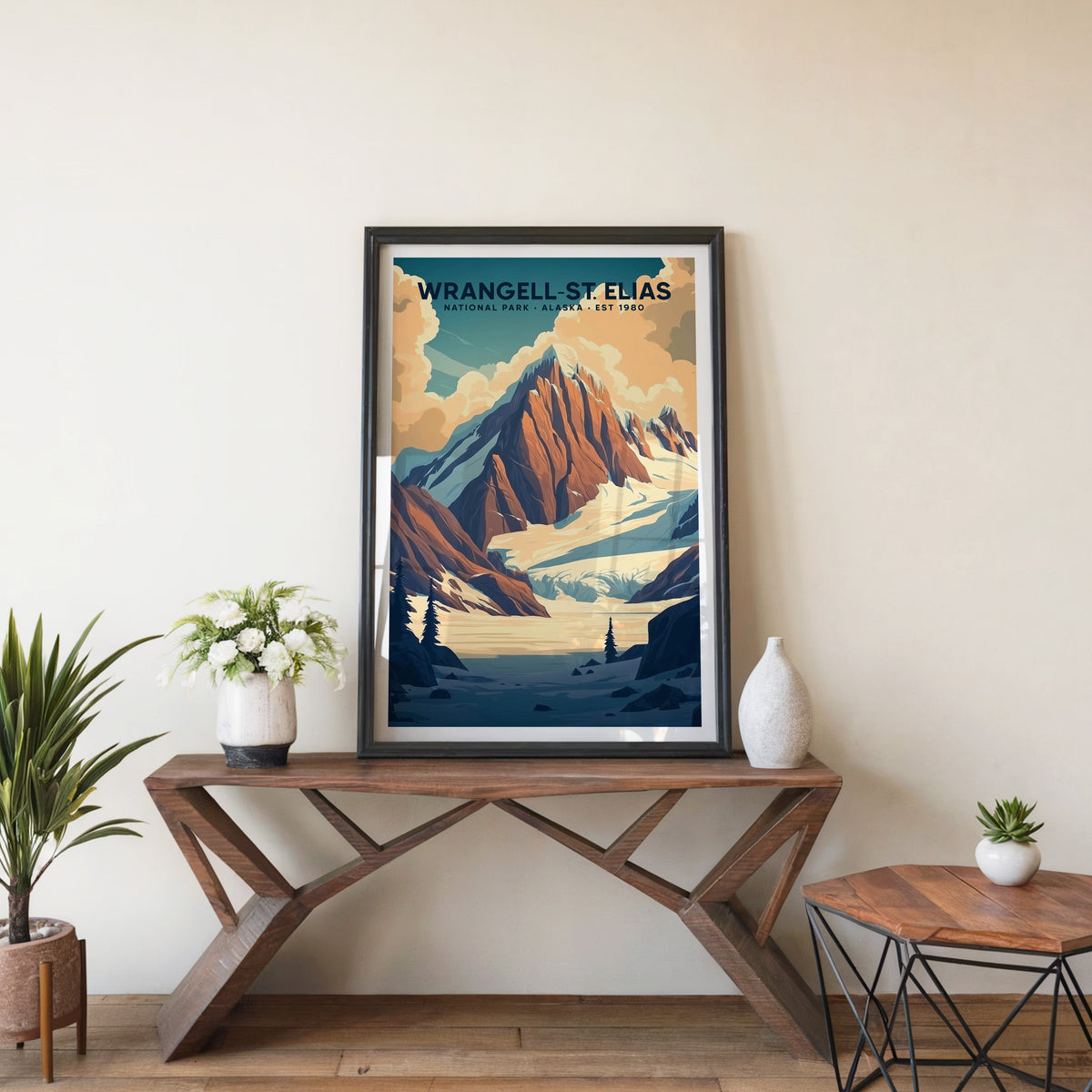 Wrangell–St. Elias poster in a black frame on an entryway console beside white flowers and a yucca