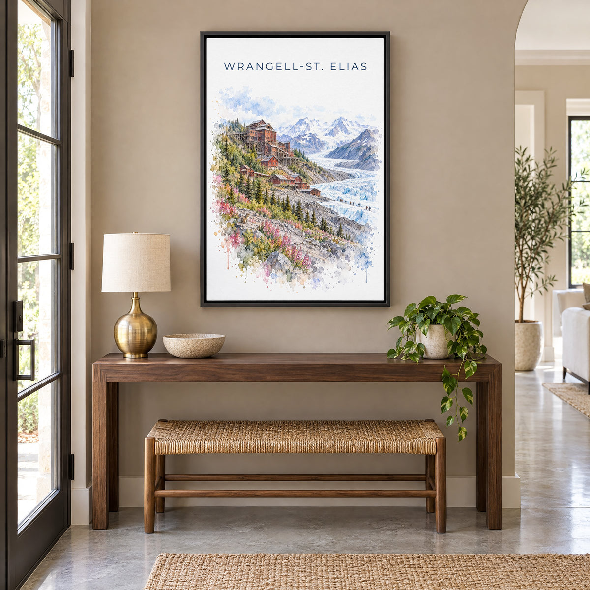Wrangell-St. Elias National Park watercolor as a black floater canvas above a walnut console and woven bench in an entryway