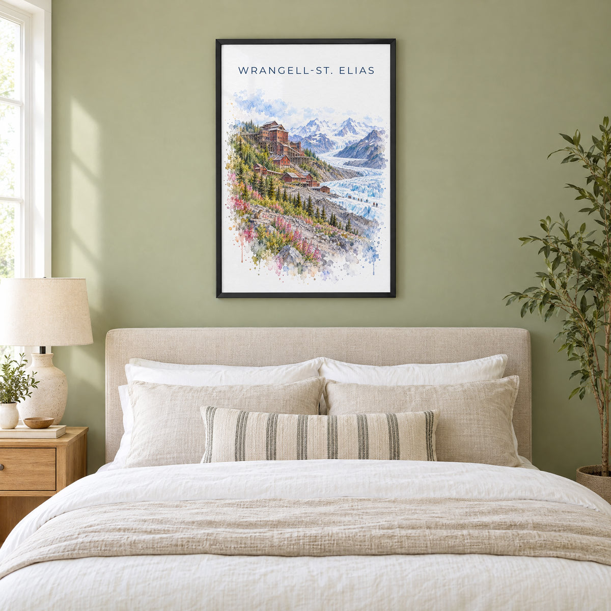 Wrangell-St. Elias National Park watercolor print in a black frame above an upholstered headboard in a sage green bedroom