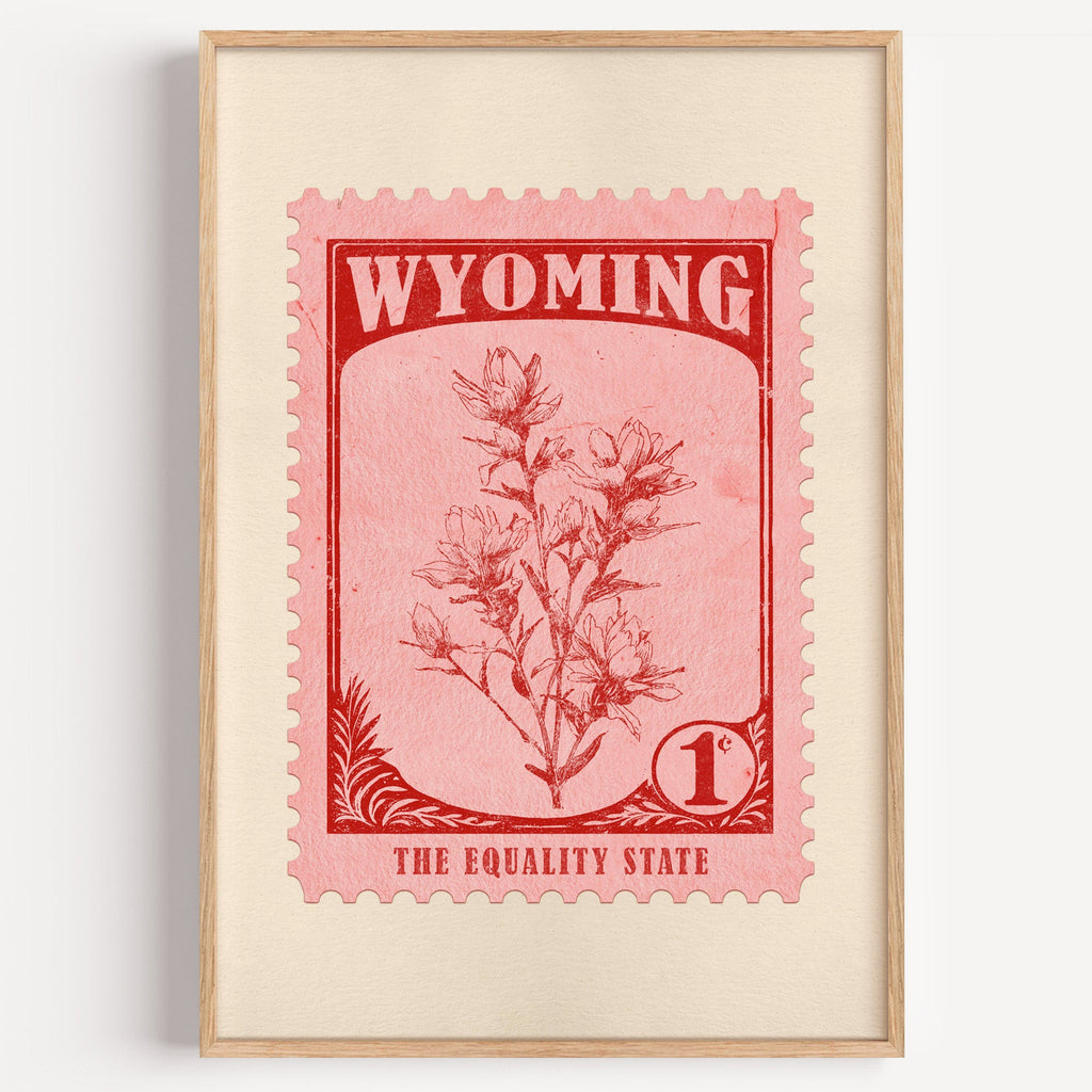 Wyoming state flower stamp print in red on pink, light oak frame on a plain white wall