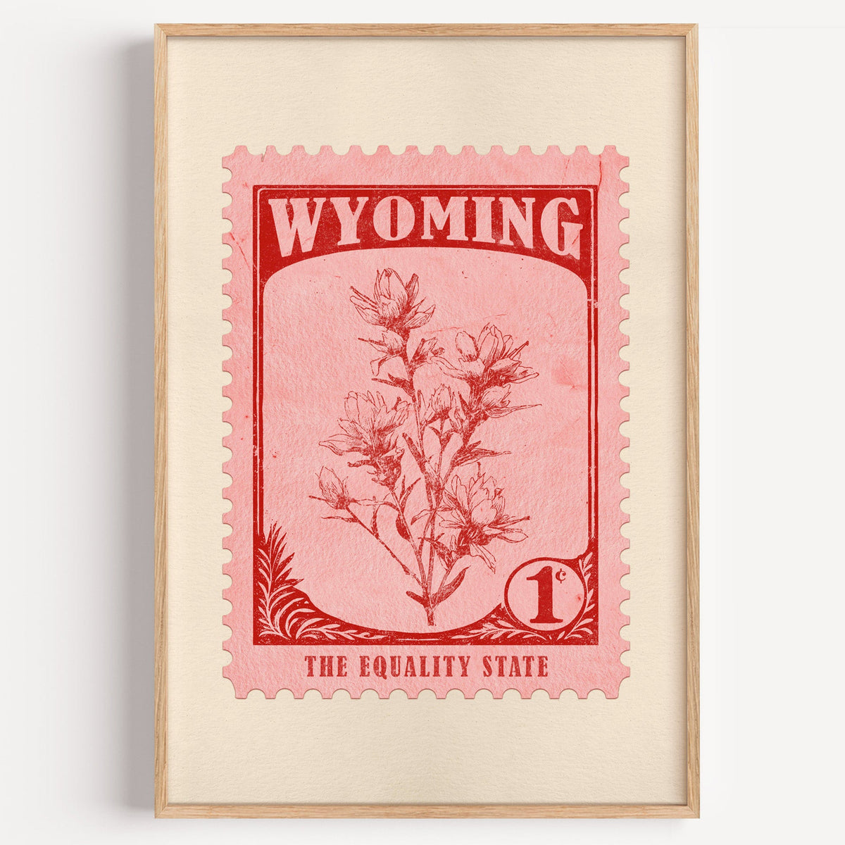 Wyoming state flower stamp print in red on pink, light oak frame on a plain white wall