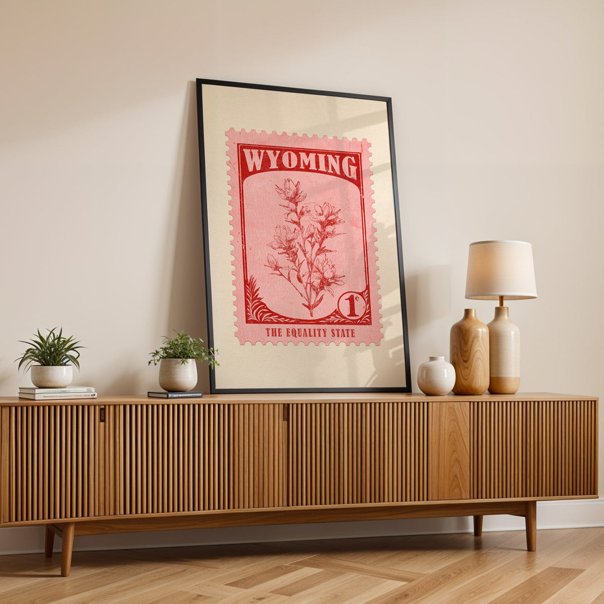 Wyoming state flower print in a black frame leaning on a fluted wood credenza with vases and a lamp