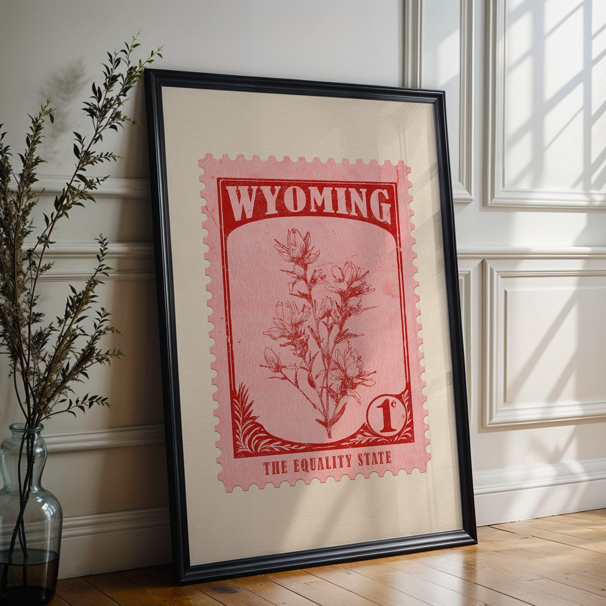 Wyoming state flower print in a black frame leaning against a white panelled wall beside olive branches