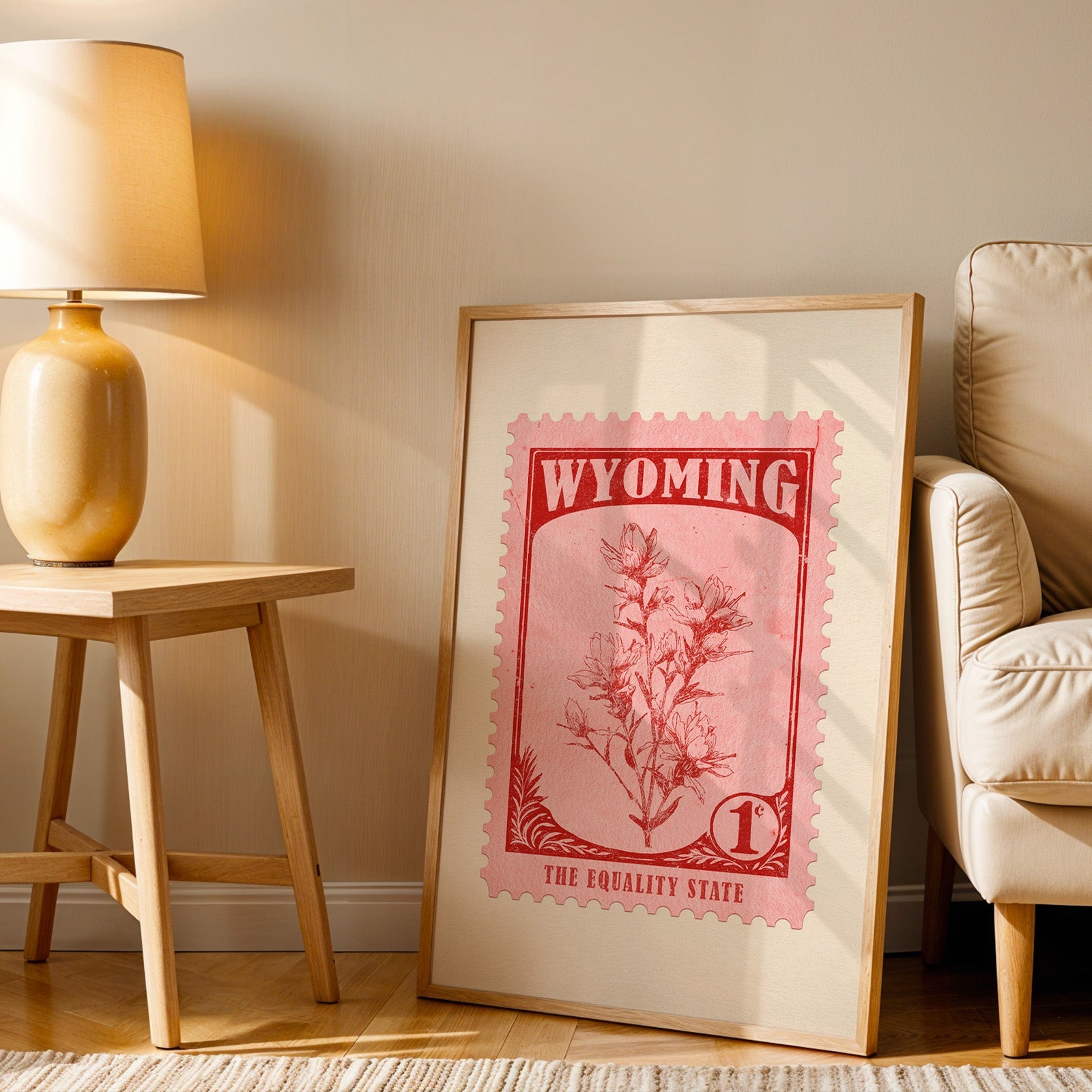 Wyoming stamp print in a wood frame resting on the floor beside a beige armchair and a yellow lamp