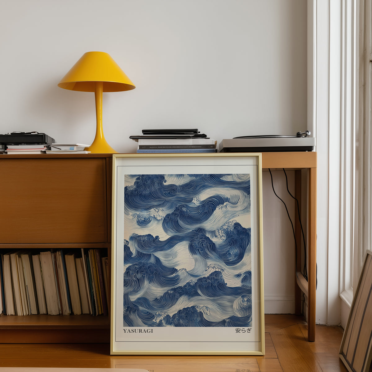 Indigo woodblock Yasuragi waves print shown in a gold frame below a teak desk with a yellow lamp