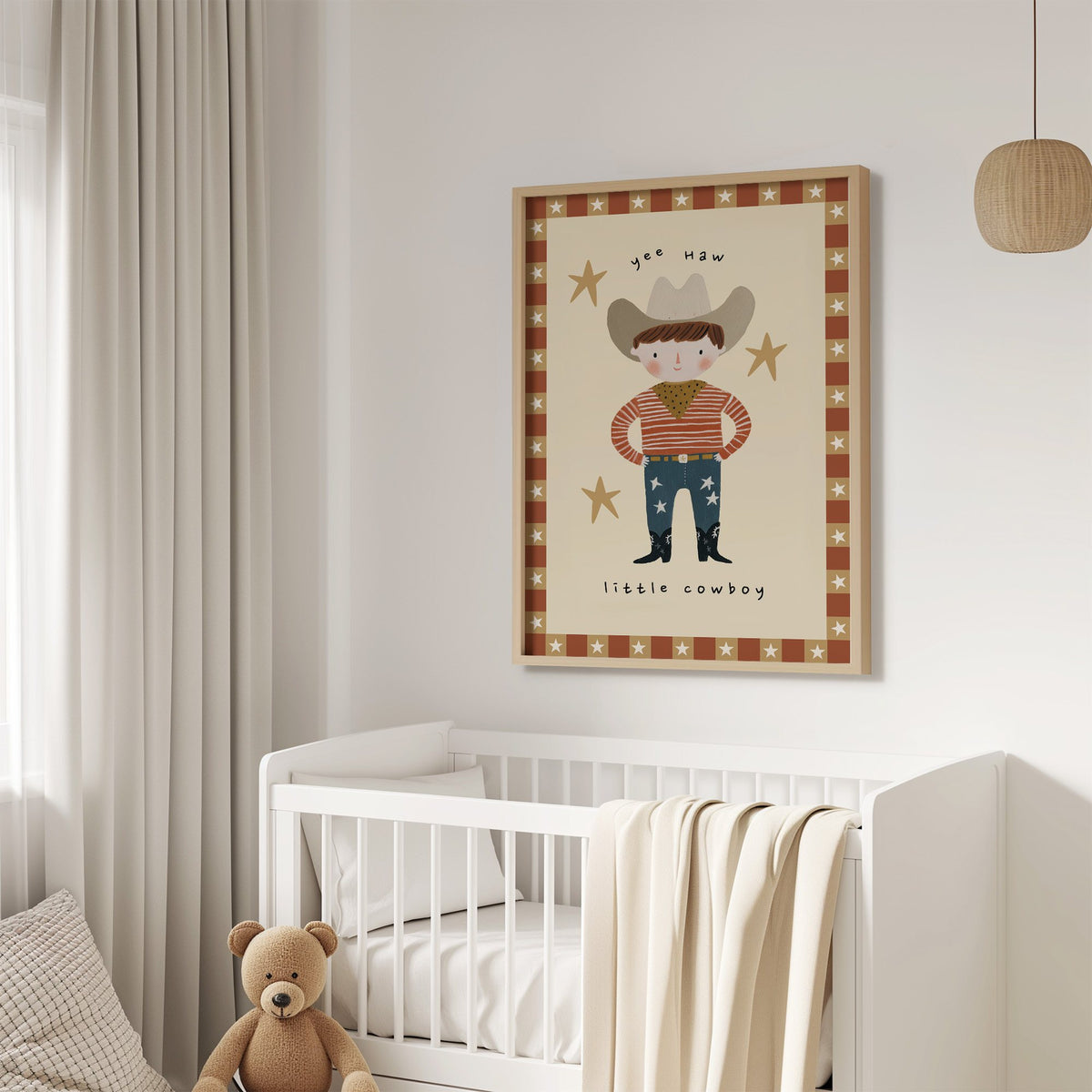 Yee haw cowboy star border nursery print in an oak frame above a white crib with a teddy bear