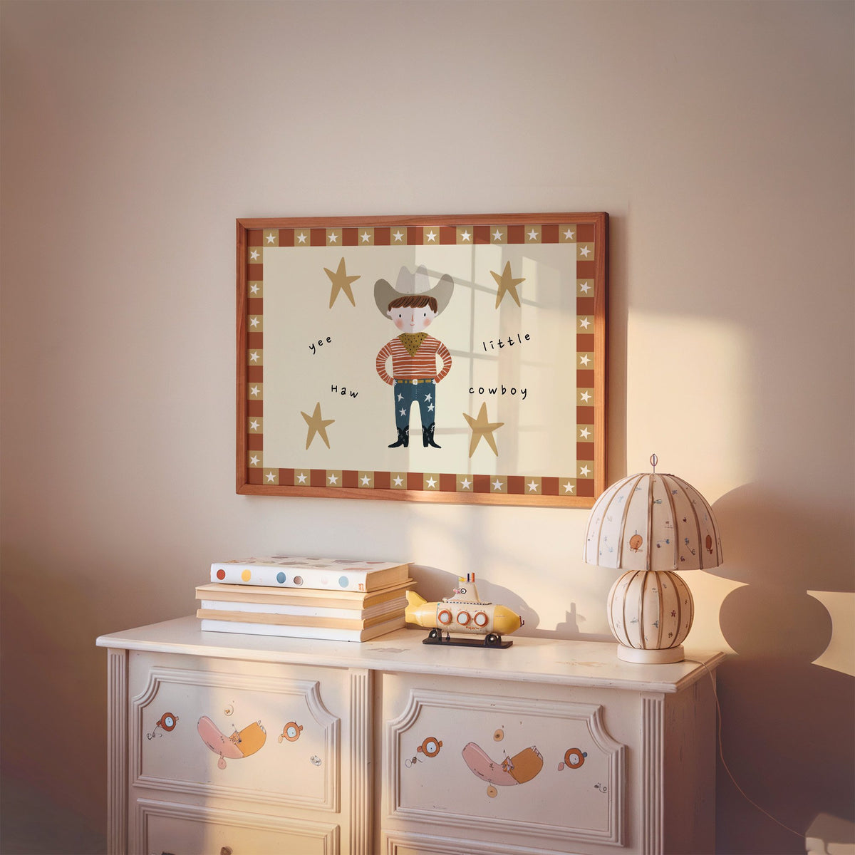 Landscape yee haw cowboy star border nursery print in a cherry wood frame above a painted dresser and lamp