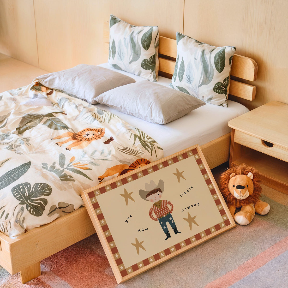 Landscape yee haw cowboy star border nursery print in an oak frame leaning on a kids bed by a lion plush
