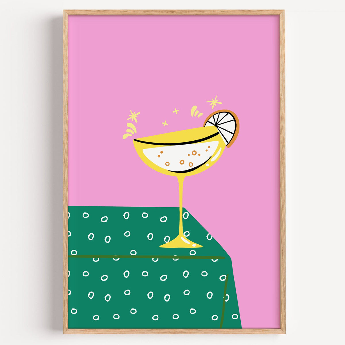Yellow coupe cocktail print in a light oak frame on a plain white wall