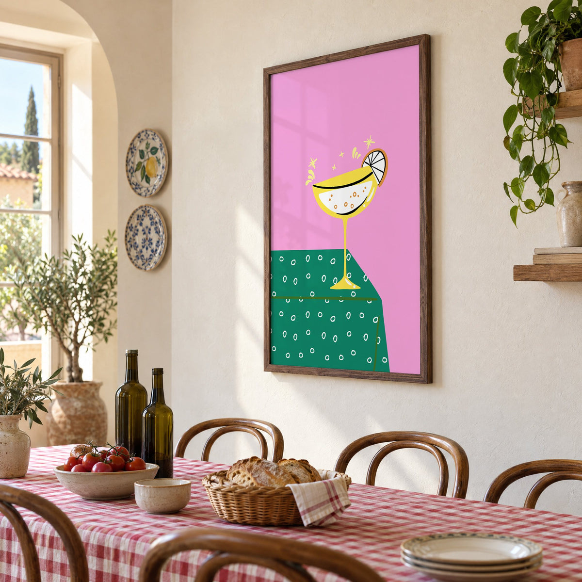 Yellow coupe cocktail print in a walnut frame above a gingham-covered trattoria table, seen at an angle