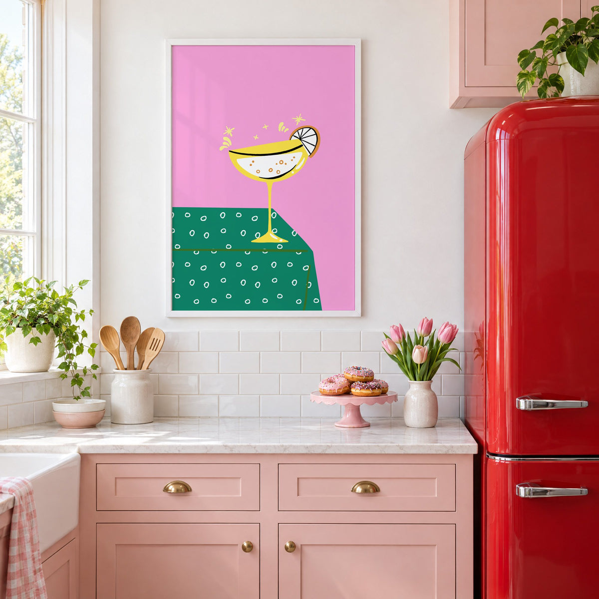 Yellow coupe cocktail print in a white frame in a pink kitchen beside a red retro fridge