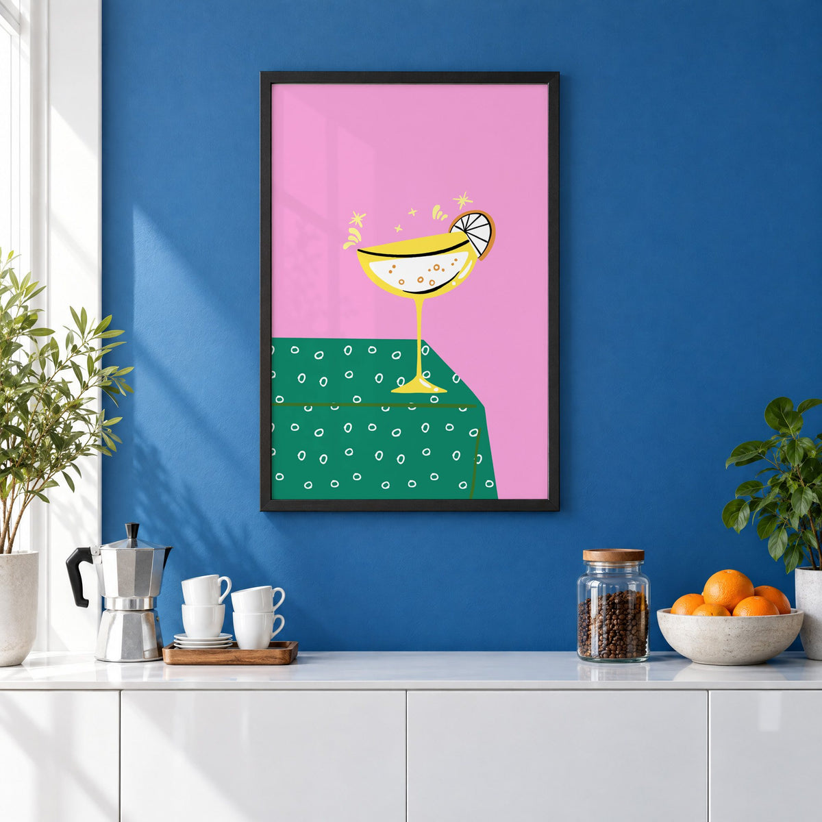 Yellow coupe cocktail print in a black frame on a cobalt blue wall above a coffee station