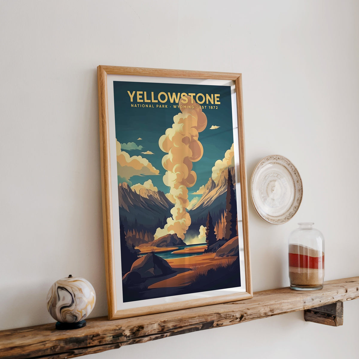 Yellowstone National Park print in an oak frame on a rustic wood shelf with ceramics and a sand jar