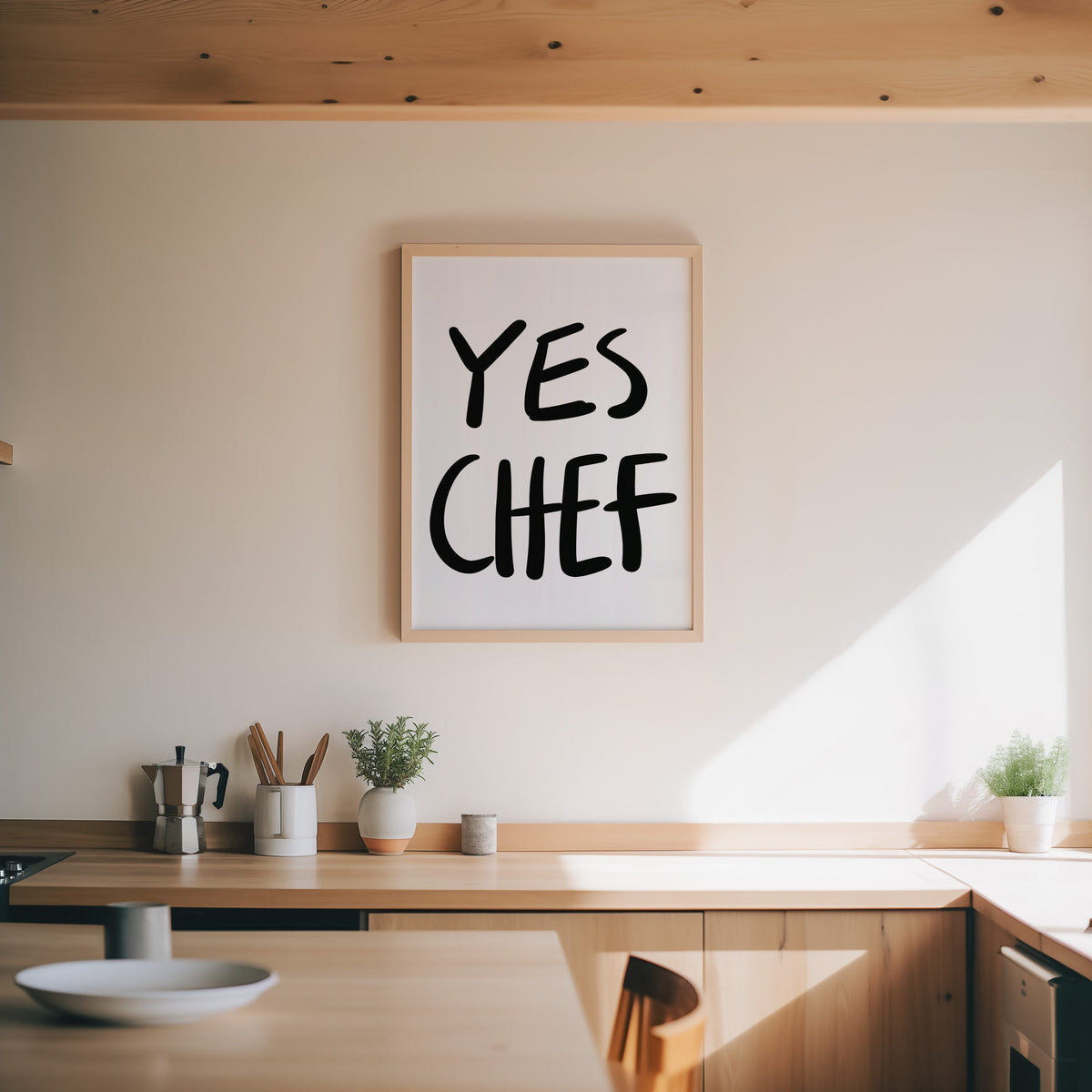Yes Chef print in an oak frame above a wood counter with a moka pot and herbs