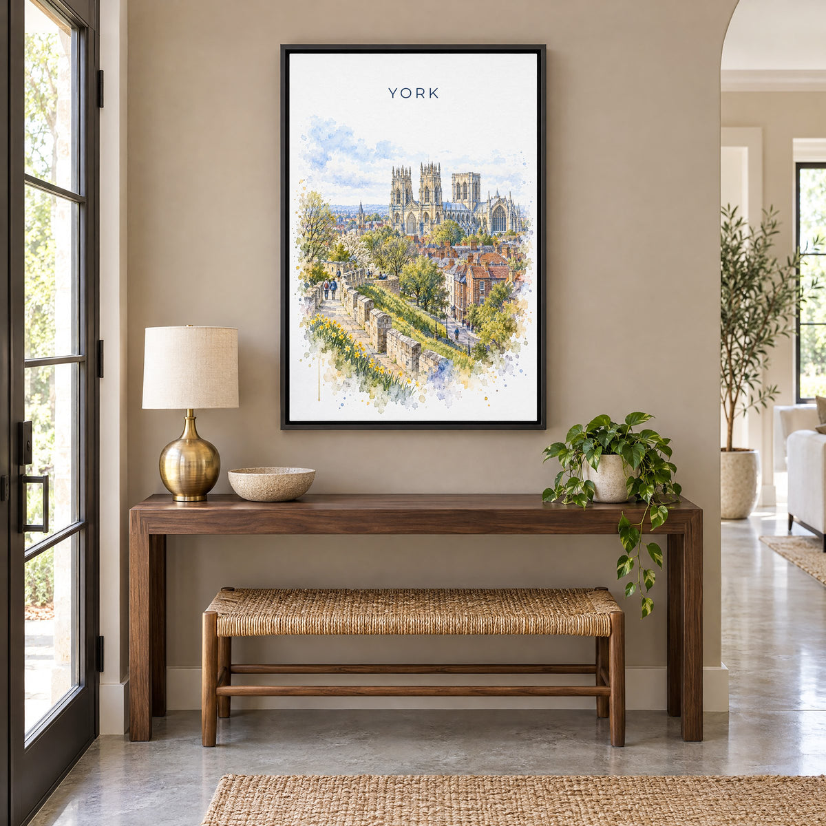 York, England watercolor print as a black floater canvas above a walnut console and woven bench in an entryway