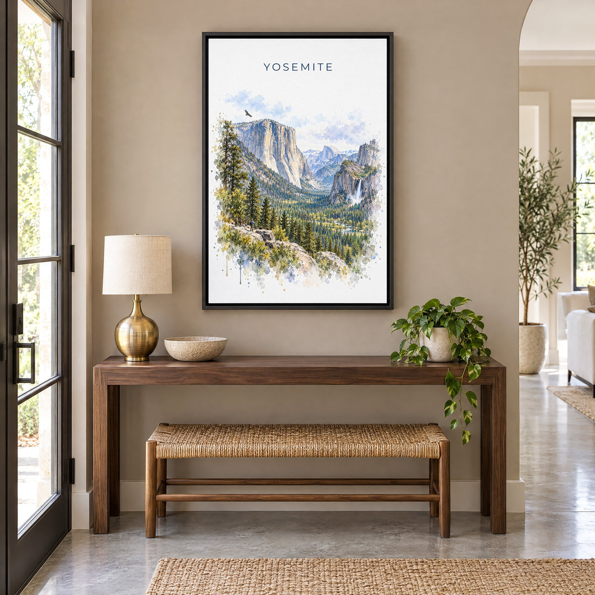 Yosemite National Park watercolor print as a black floater canvas above a walnut console and woven bench in an entryway