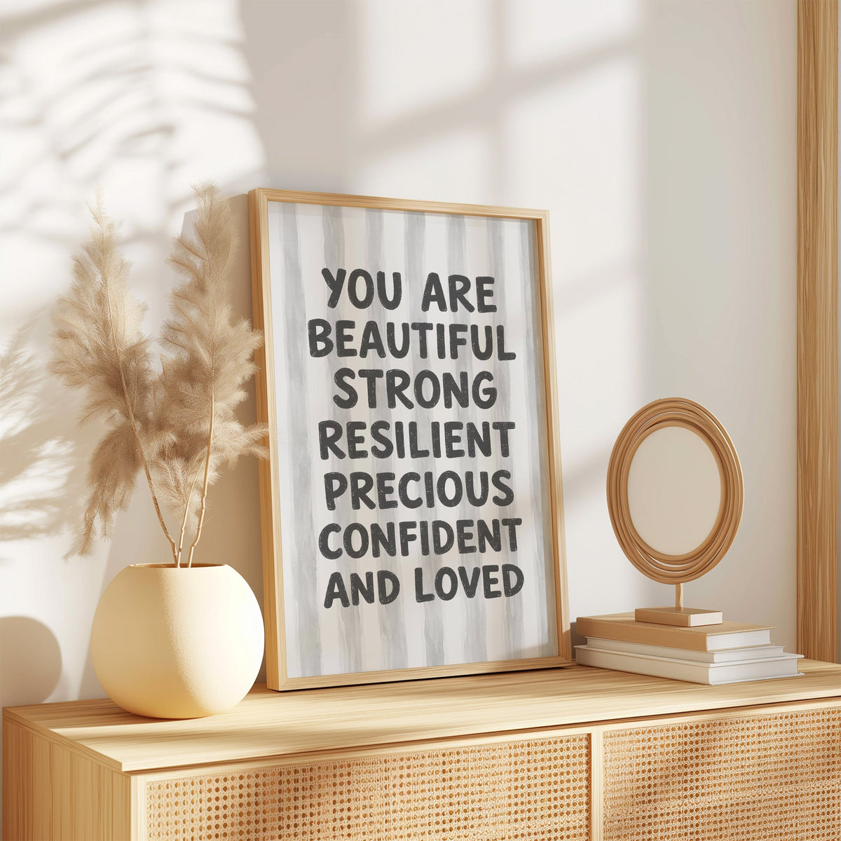 You are beautiful affirmation quote print in an oak frame on a rattan sideboard beside pampas grass