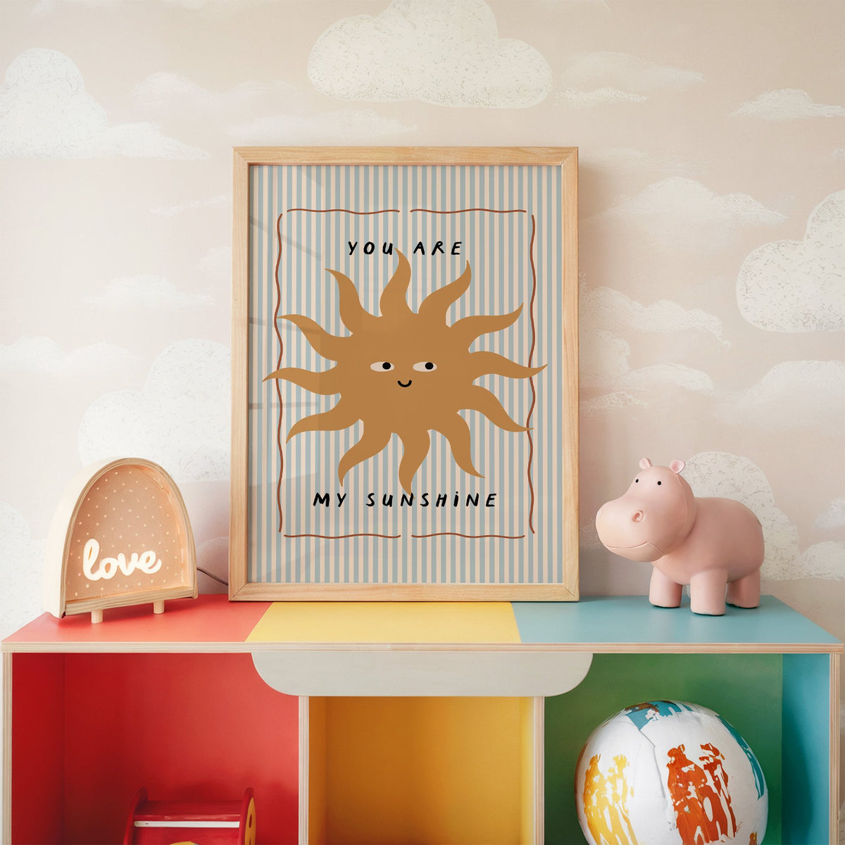You are my sunshine sun nursery print in an oak frame on a rainbow toy shelf against cloud wallpaper