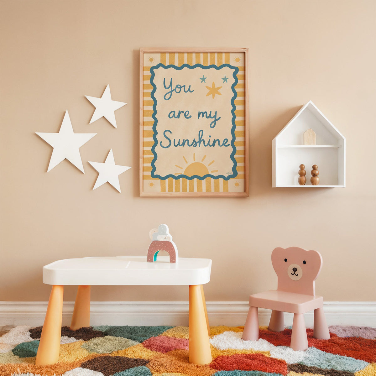 You are my sunshine wavy frame nursery print in an oak frame on a peach wall above a kids table with wall stars