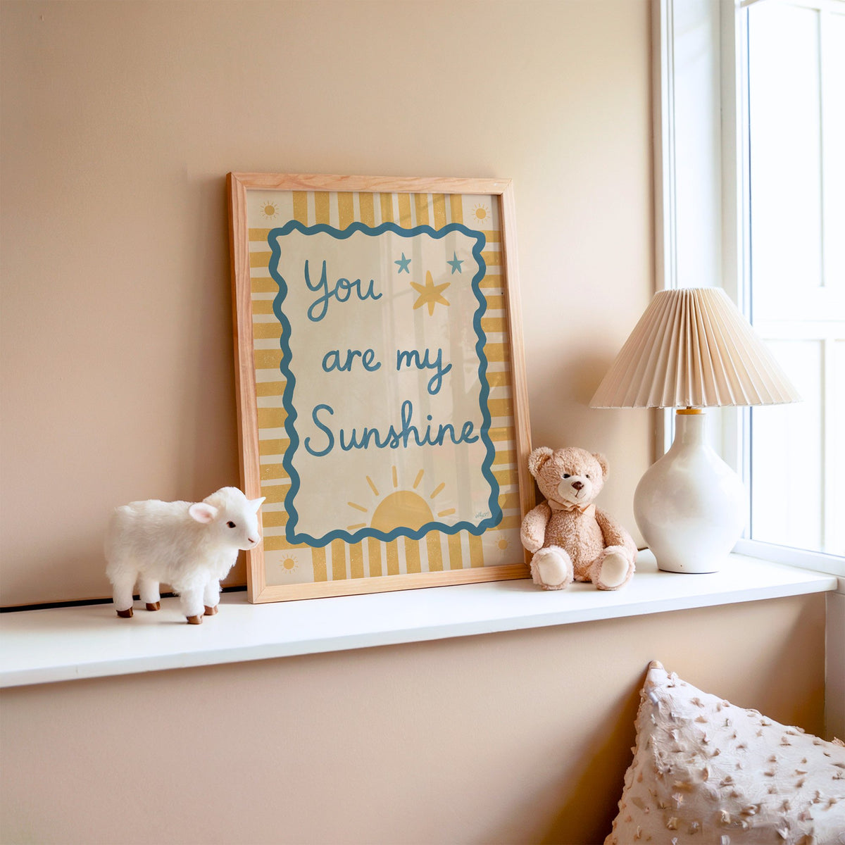 You are my sunshine wavy frame nursery print in an oak frame on a window ledge with a toy lamb and teddy