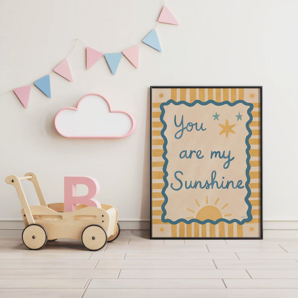 You are my sunshine wavy frame nursery print in a black frame under pastel bunting by a wooden baby walker