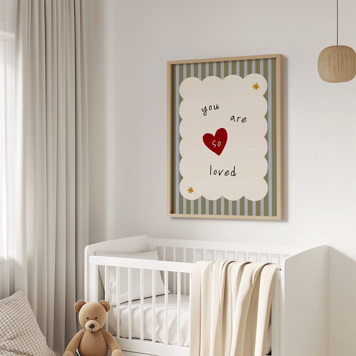 You are so loved heart nursery print in an oak frame above a white crib with a teddy bear