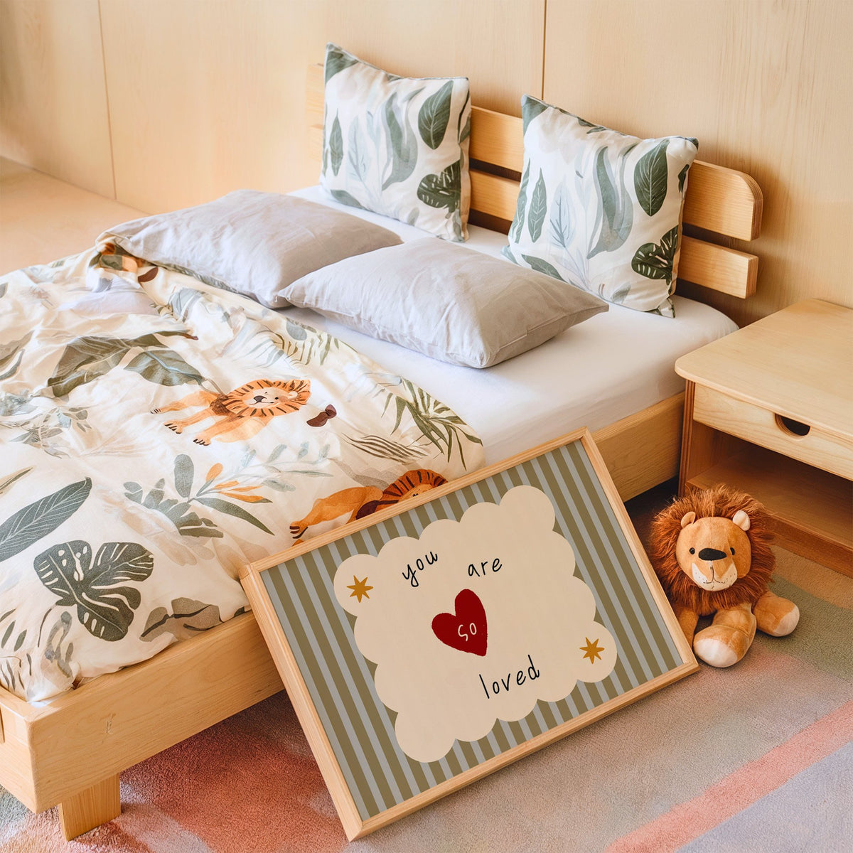 Landscape you are so loved heart nursery print in an oak frame leaning on a kids bed by a lion plush