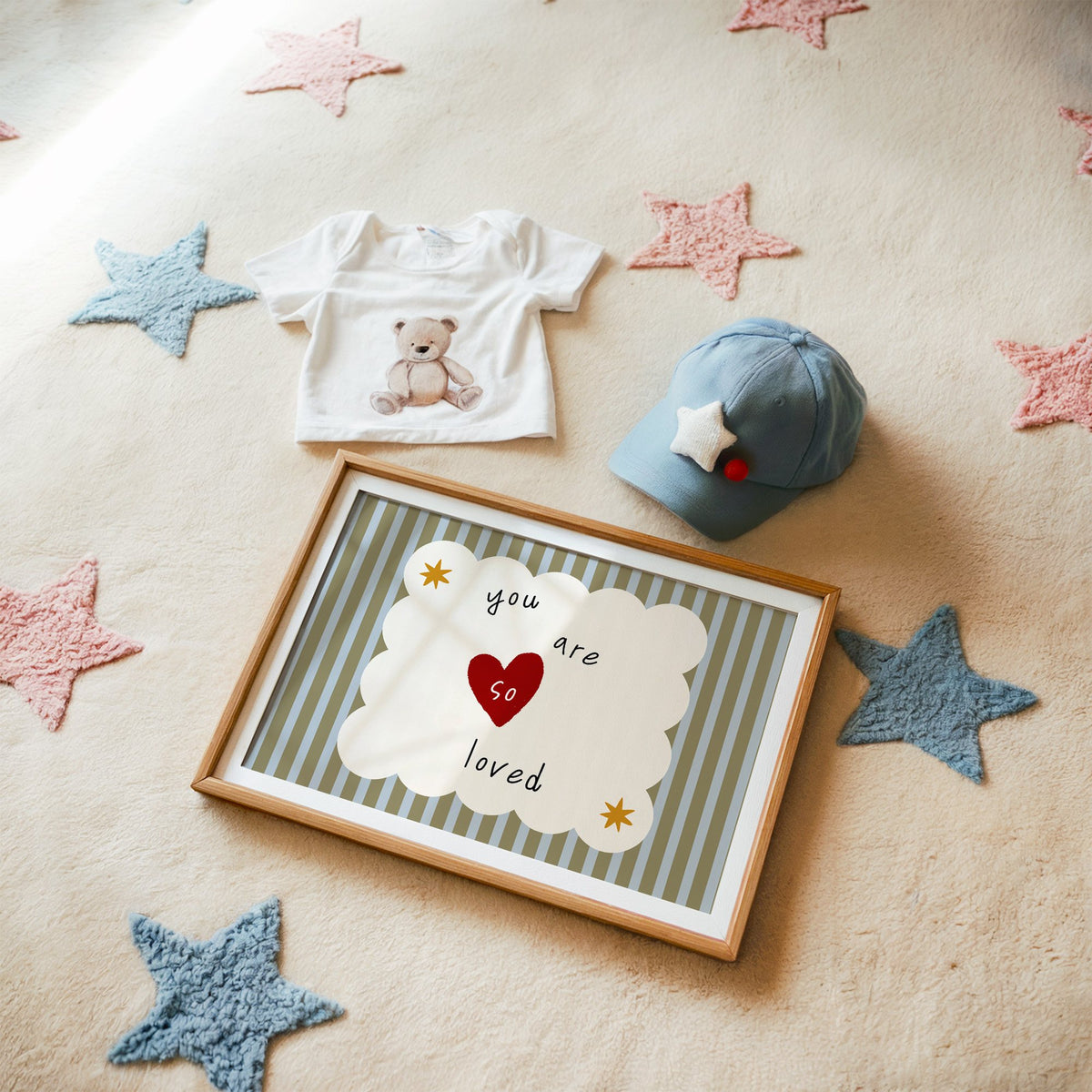 Landscape you are so loved heart nursery print in a matted oak frame on a star rug with a baby tee