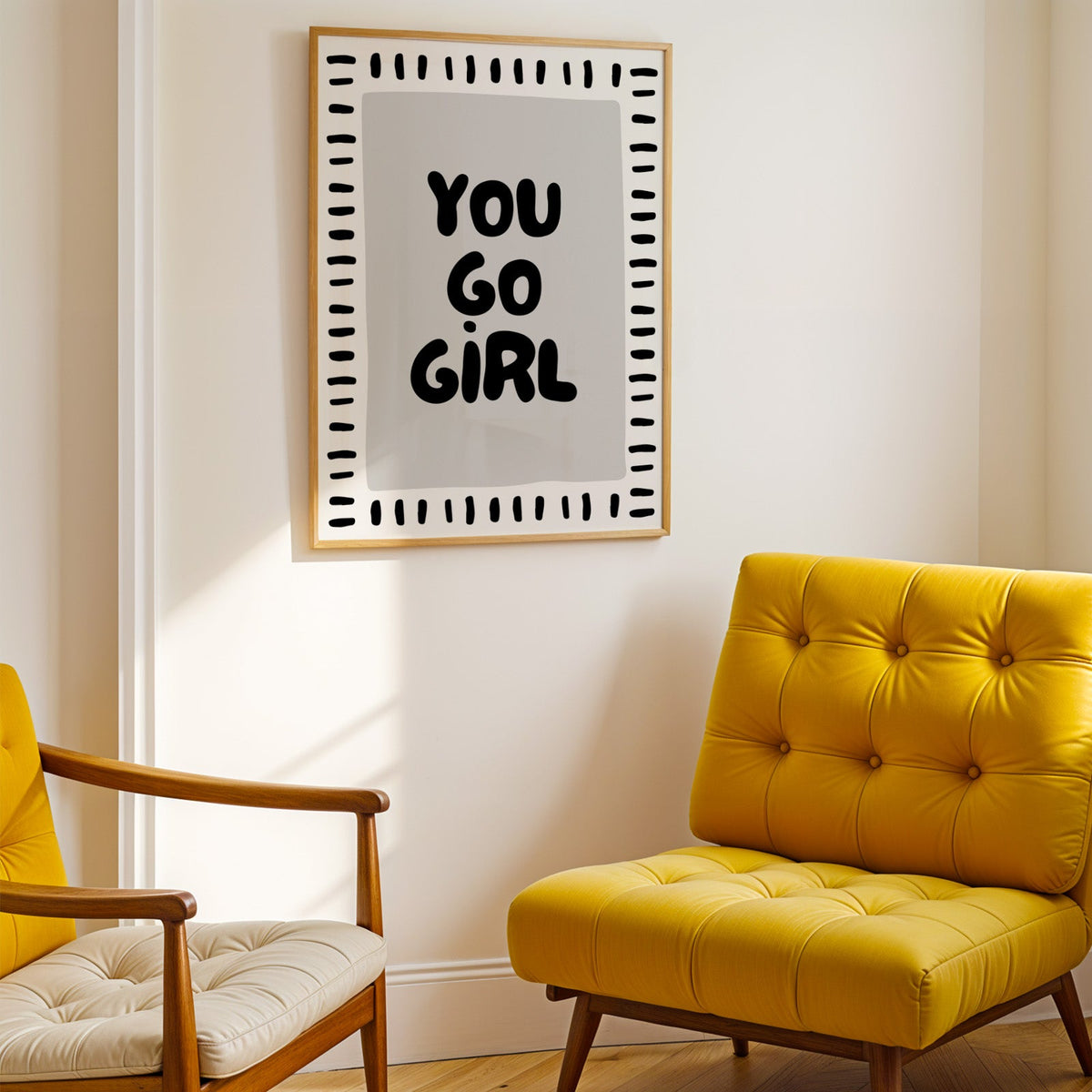 You go girl bubble letter quote print shown in a gold frame above a mustard yellow tufted armchair
