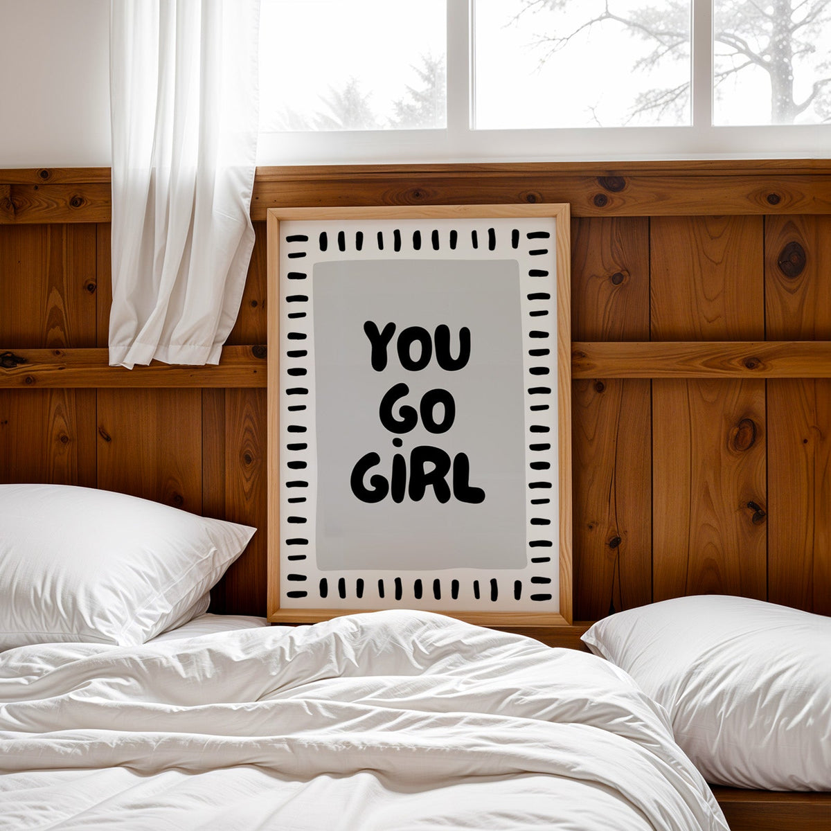 You go girl bubble letter quote print in a pine frame leaning on a wood headboard over white bedding