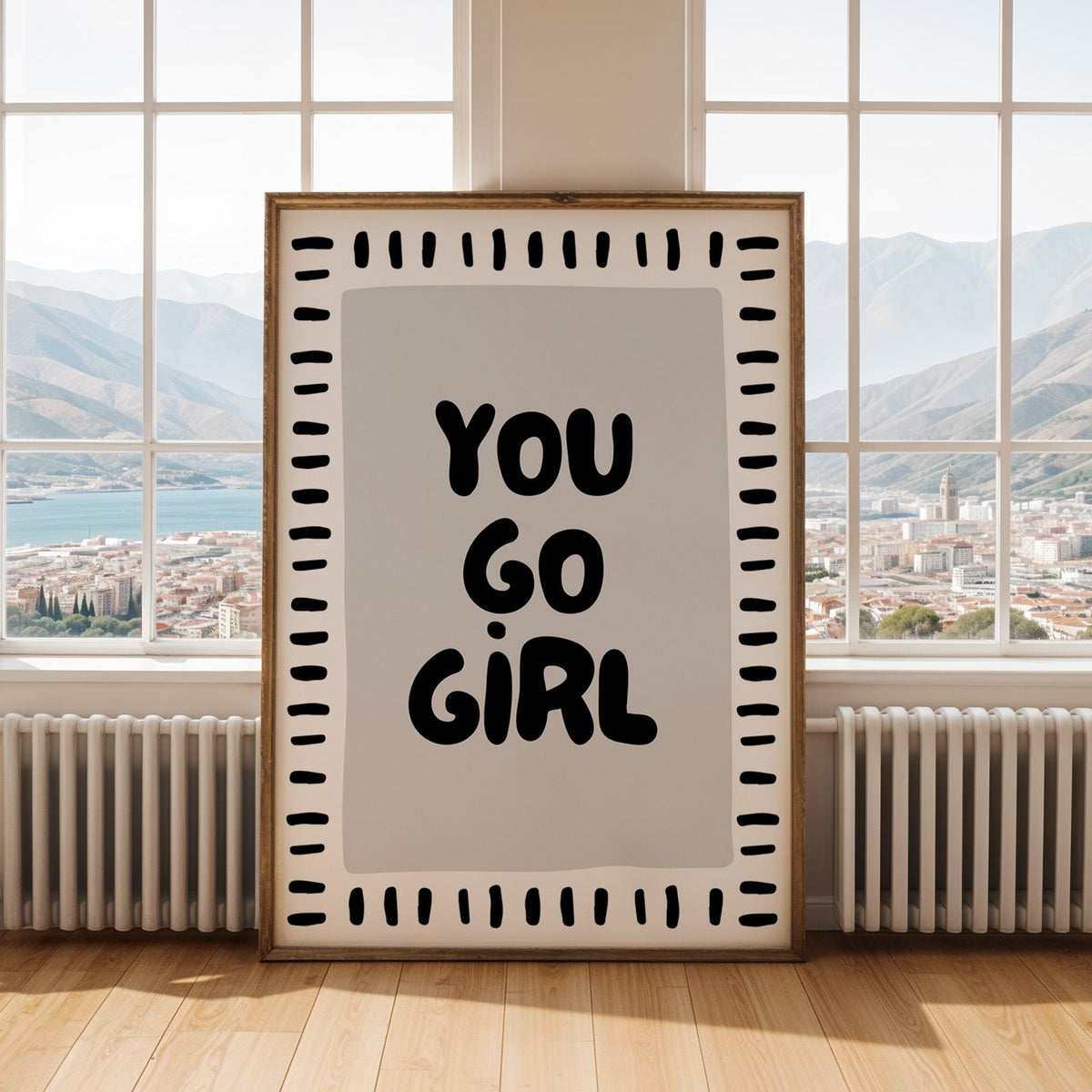 You go girl bubble letter quote print shown in an antique gold frame by tall windows with a sea view