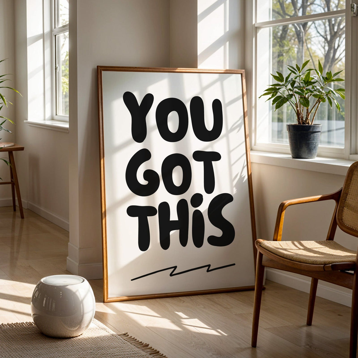 You got this bubble letter quote print in a walnut frame on a wood floor beside a cane chair and sunny window