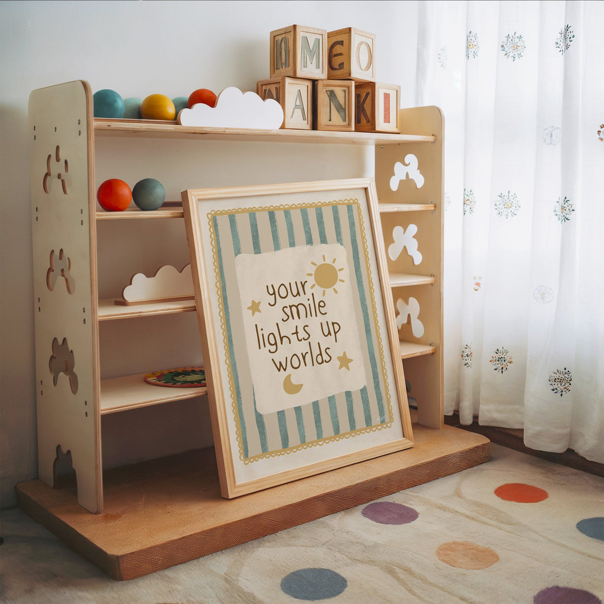 Your smile lights up worlds nursery print in an oak frame leaning on a toy shelf with wooden letter blocks