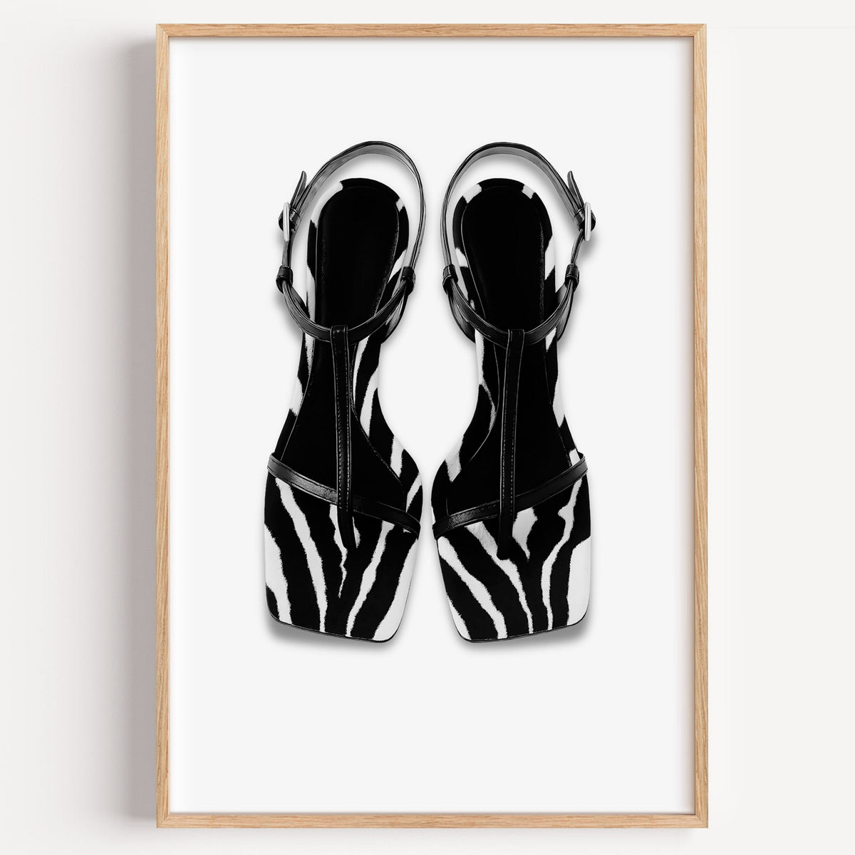 Zebra stripe T-strap sandals on white print in a light oak frame on a plain white wall