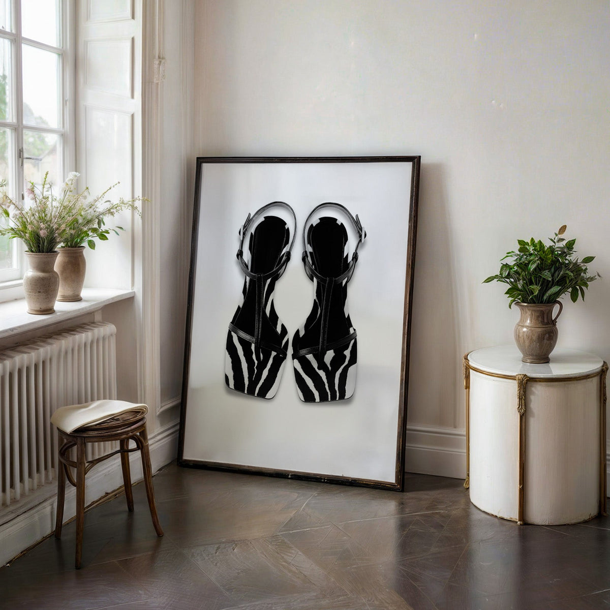 Zebra stripe T-strap sandals on white print in a black frame on a dark stone floor beside a white side table