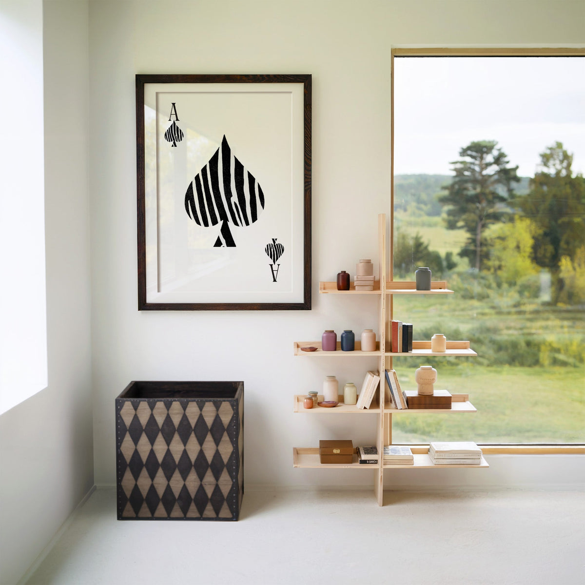 Zebra stripe ace of spades playing card print in a walnut frame with a white mat beside wooden shelves and a garden window