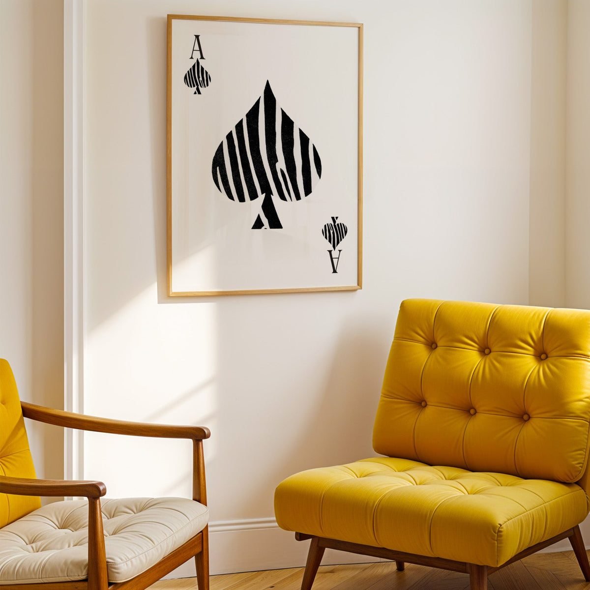Zebra stripe ace of spades playing card print shown in a gold frame above a mustard yellow tufted armchair