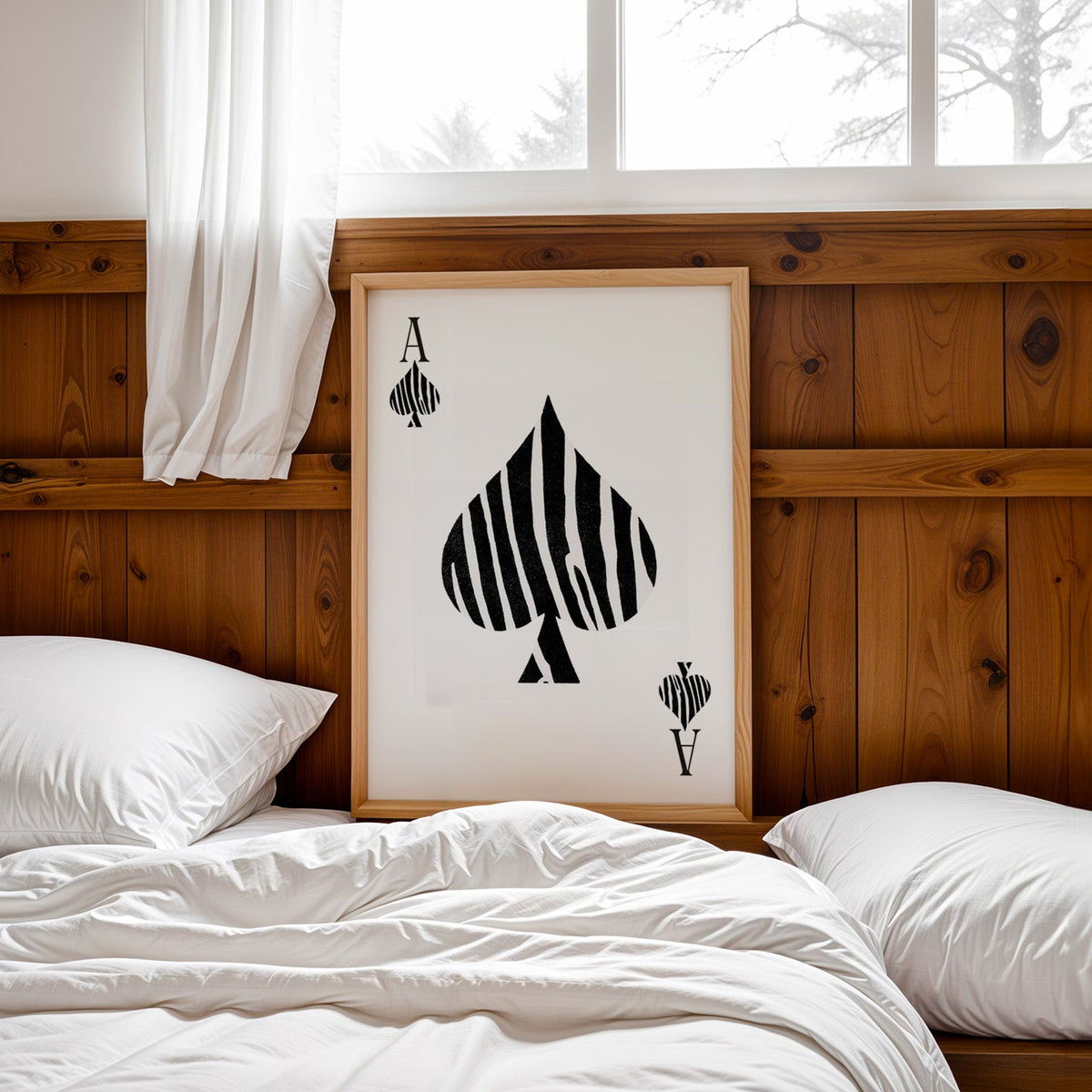 Zebra stripe ace of spades playing card print in a pine frame leaning on a wood headboard over white bedding