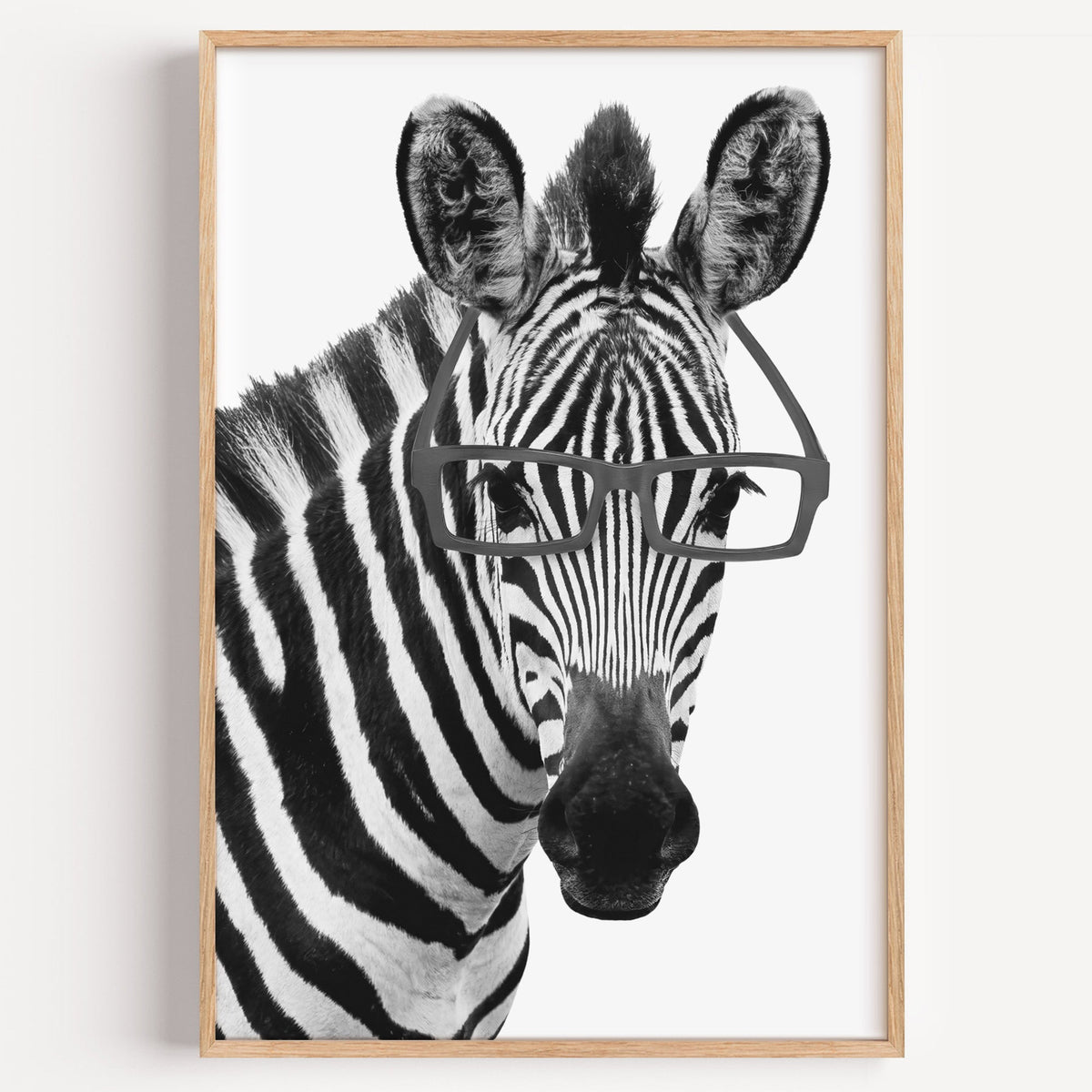 Zebra wearing black rectangular glasses print in a light oak frame on a plain white wall