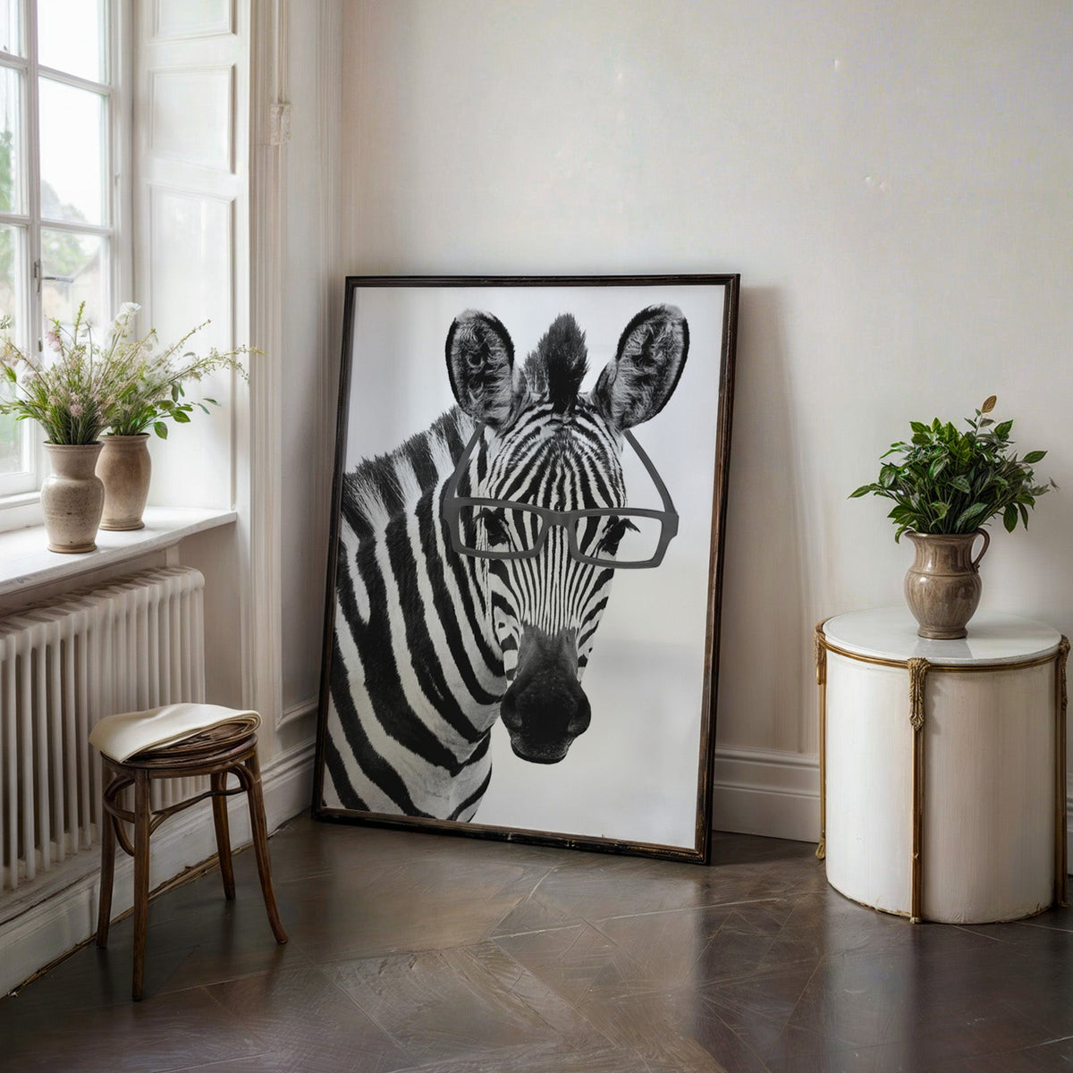 Zebra wearing black rectangular glasses print in a black frame on a dark stone floor beside a white side table