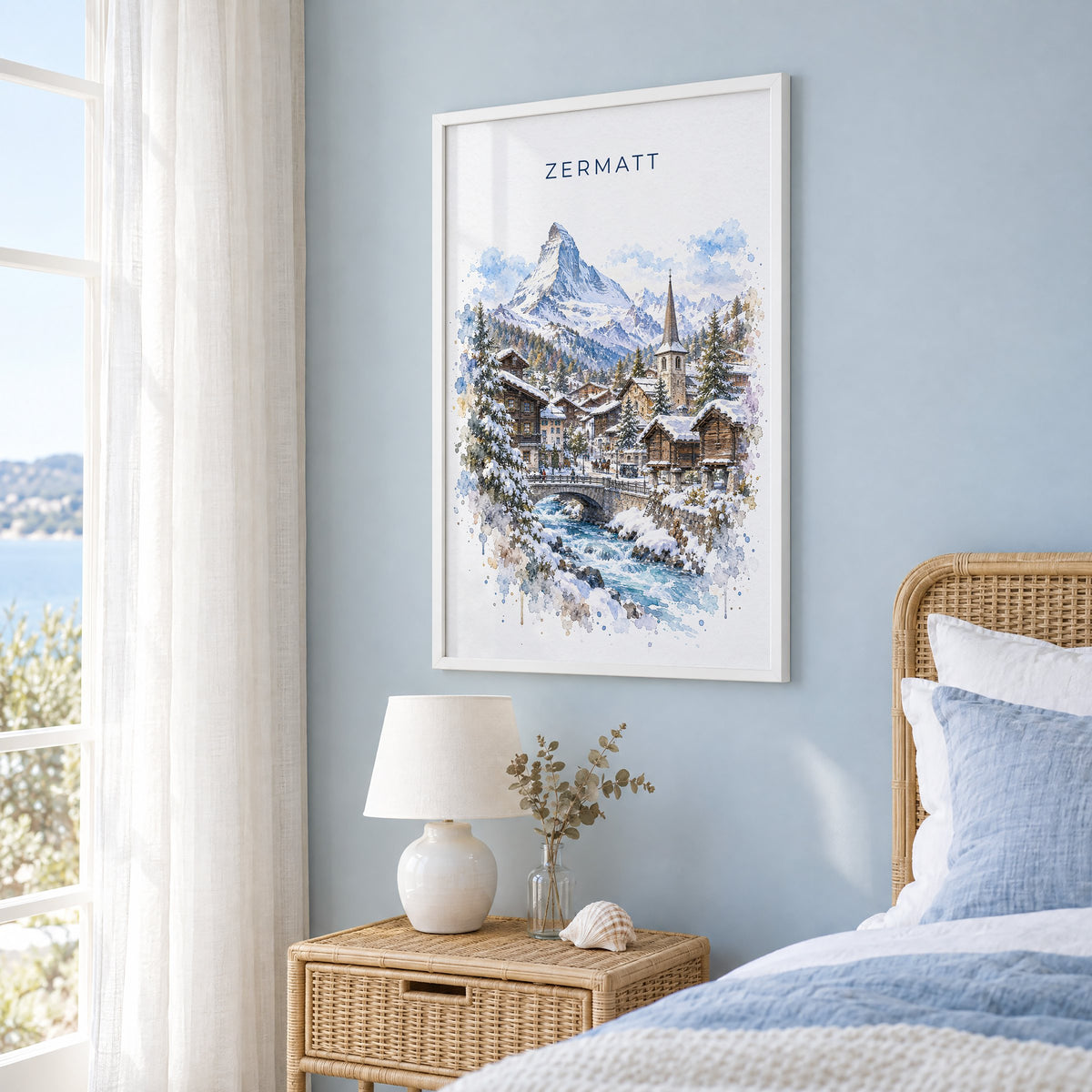 Zermatt watercolor print in a white frame on a pale blue wall beside a rattan bed in a coastal bedroom