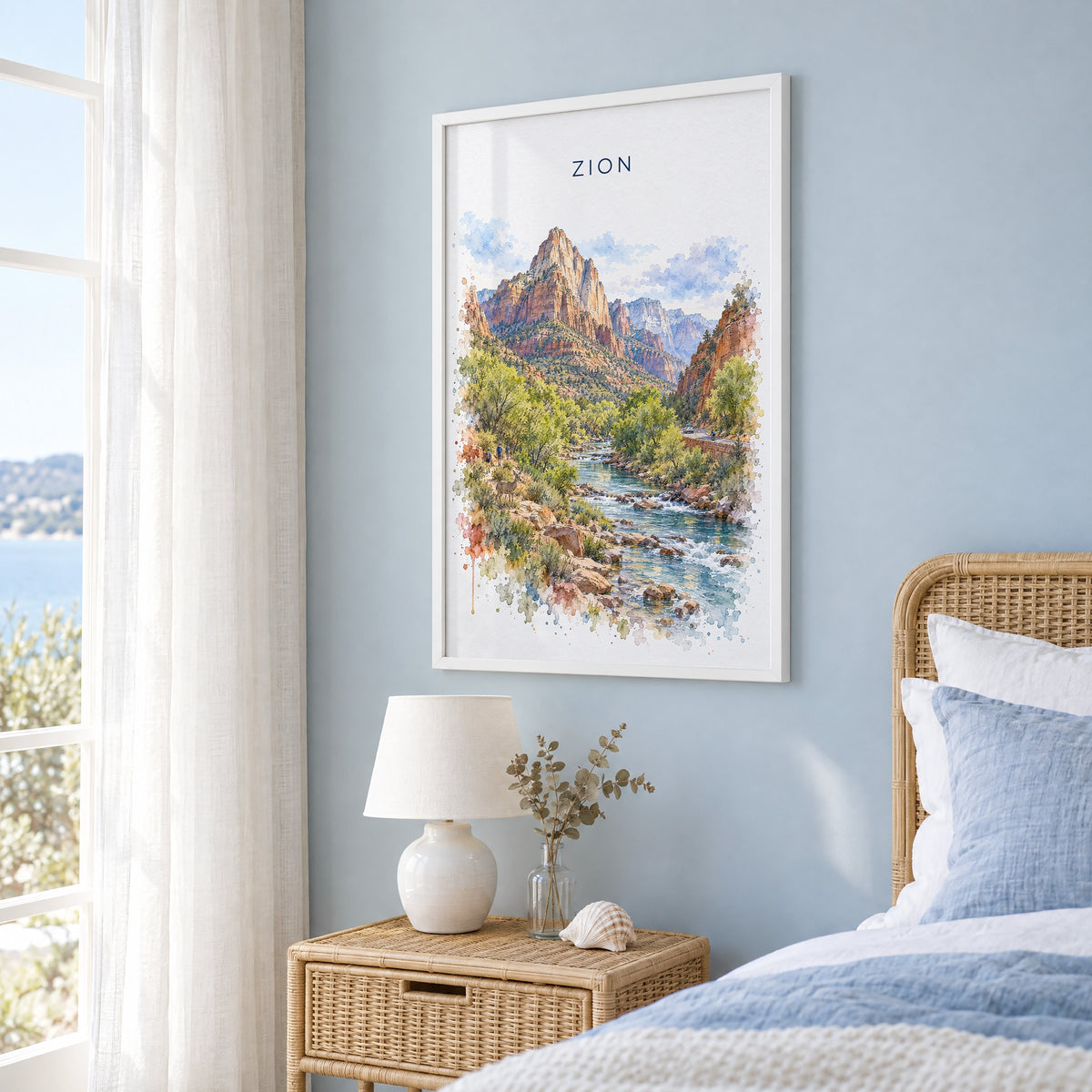 Zion National Park watercolor print in a white frame on a pale blue wall beside a rattan bed in a coastal bedroom